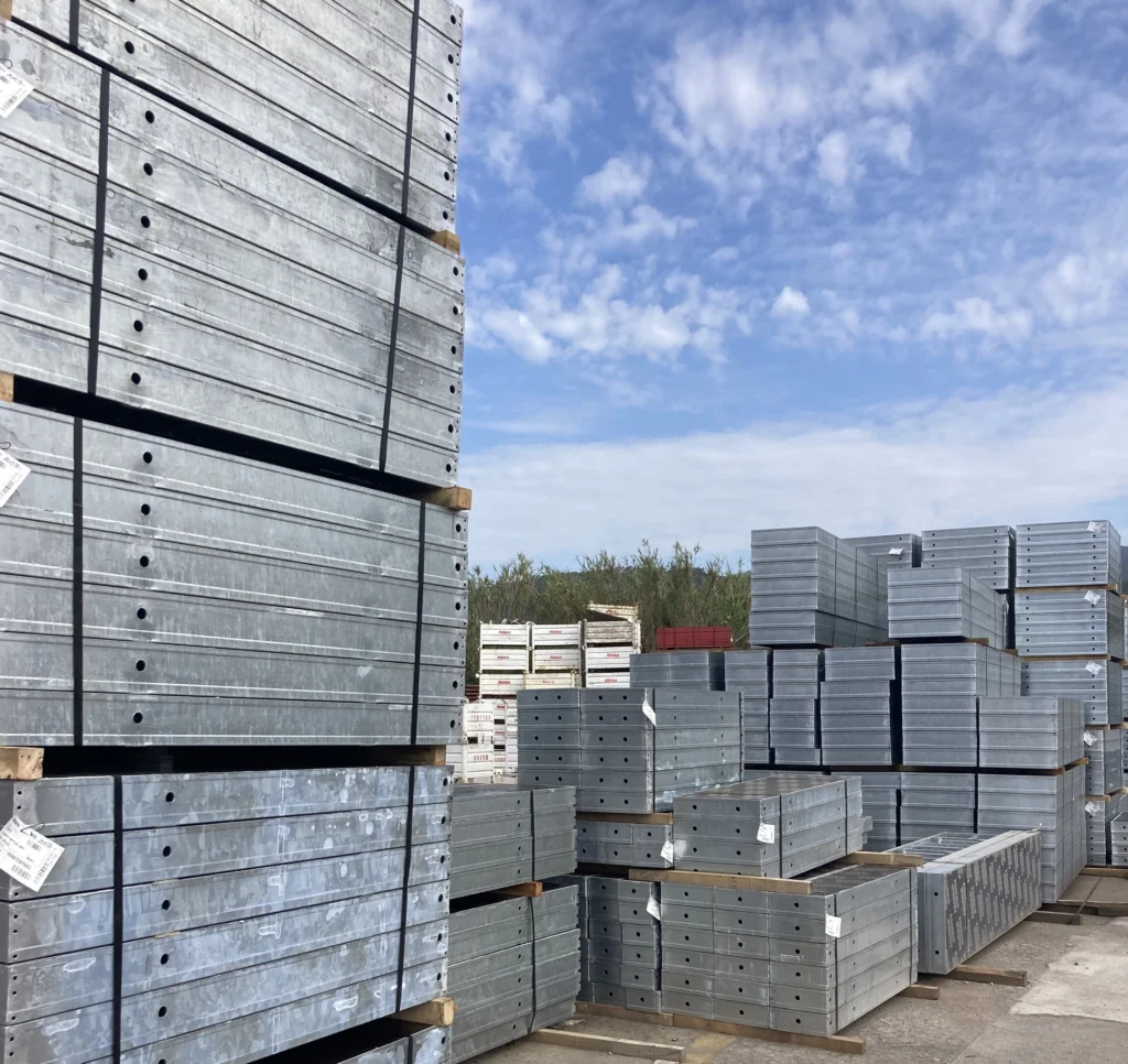 Vista general de grandes volúmenes de encofrados metálicos apilados en almacén al aire libre, caso de éxito Alsina en la gestión de activos industriales en construcción
