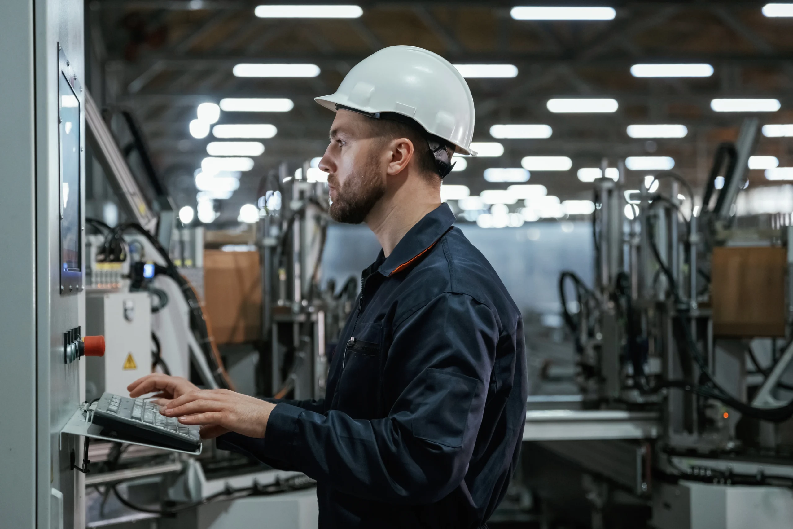 operario supervisando procesos industriales desde un panel de control en planta automatizada