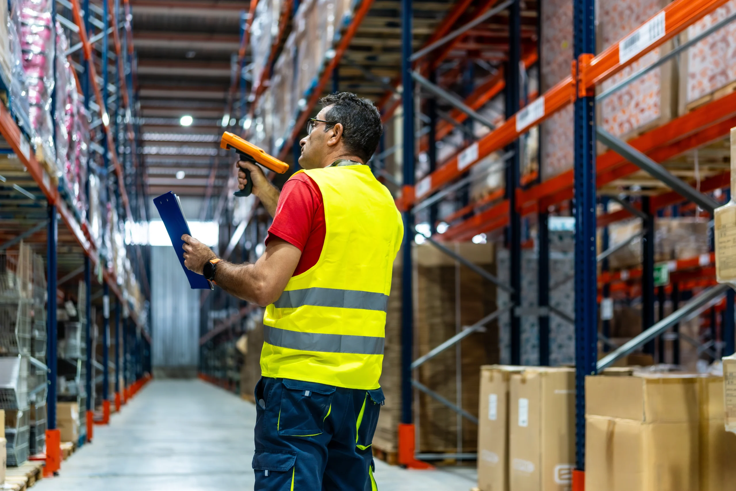 Operario realizando inventario en almacén con lector y hoja de control